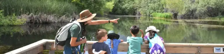 Group of children and a woman observing wildlife on a boat tour at Wildlands Conservancy.
