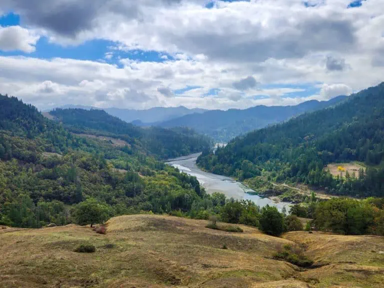 Beautiful landscape of Eel Rock Ranch with river and mountains under cloudy sky.