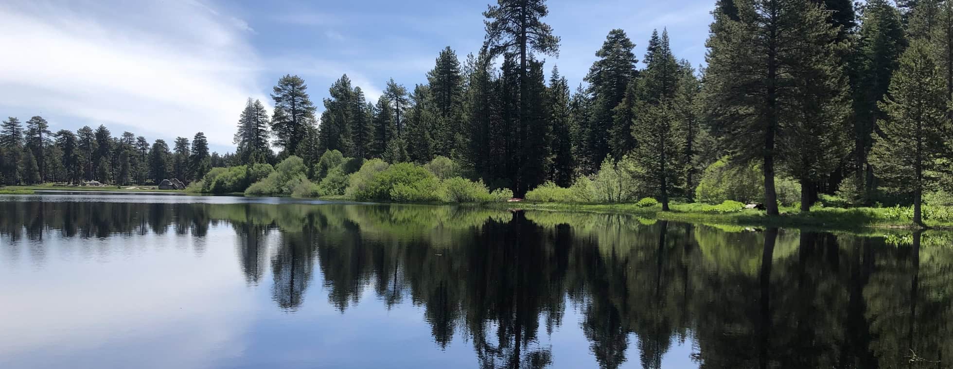Wildlands Conservancy lake with calm water and lush forest backdrop.