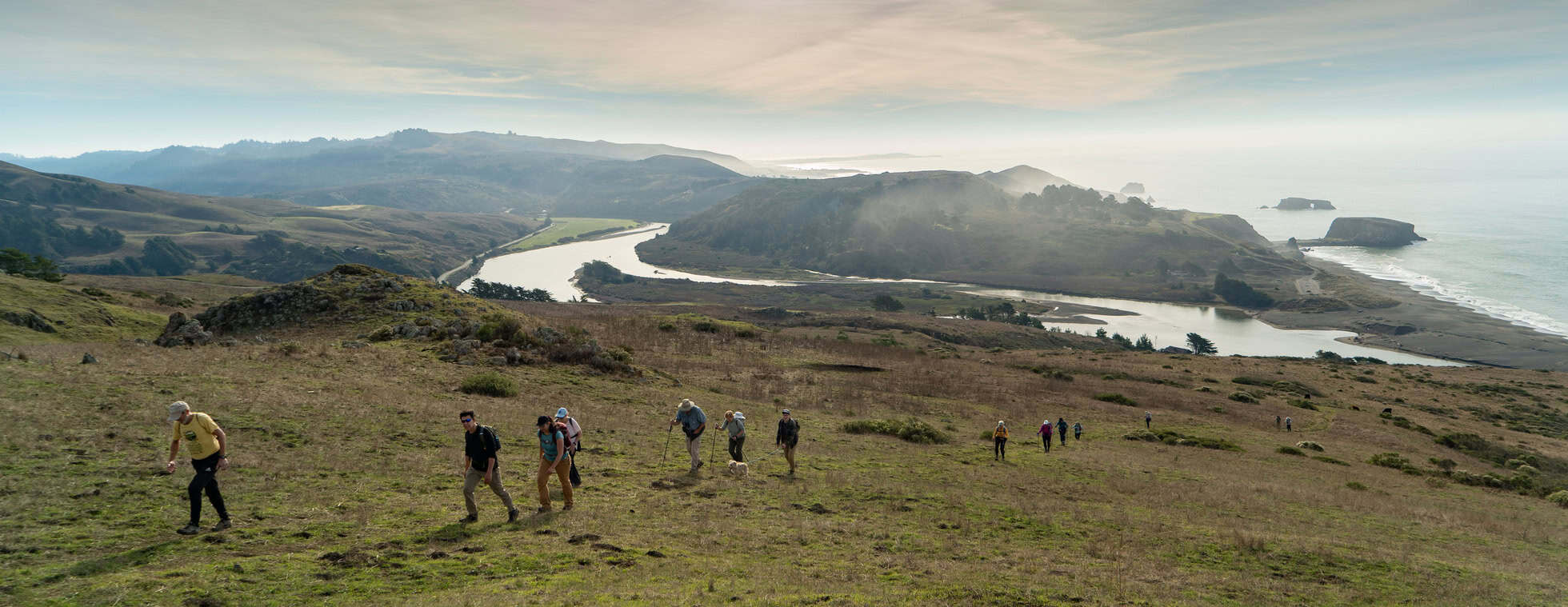 Hikers exploring the scenic Jenner Headlands with ocean views in the background.