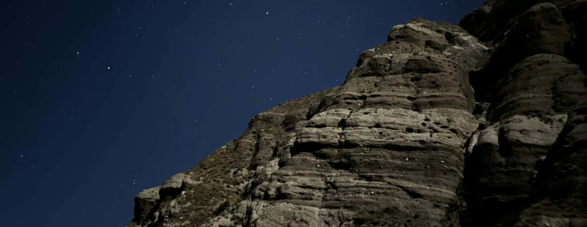 Starry night sky above rugged rocky cliffs at Wildlands Conservancy.
