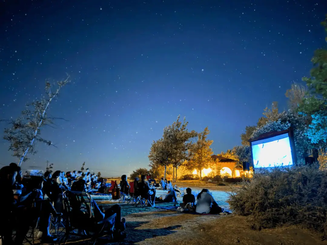 People watching an outdoor movie under a starry night sky at The Wildlands Conservancy.